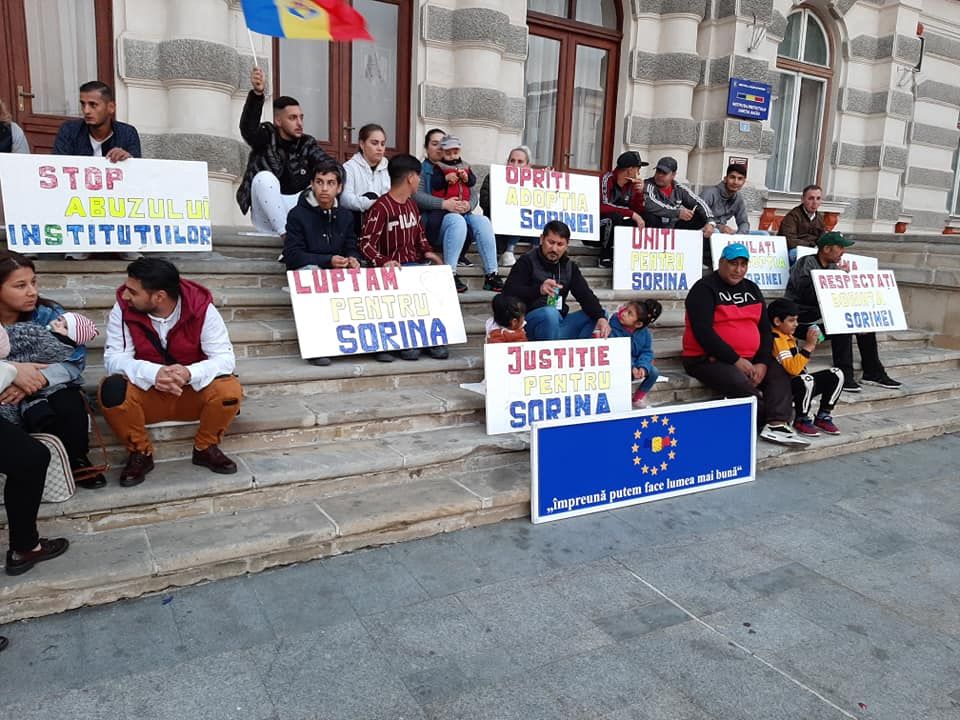 GALERIE FOTO:„Luptăm pentru Sorina!”. Protest inedit pe treptele Prefecturii Bacău pentru anularea adopției internaționale a fetiței de opt ani luată de lângă familia în care a crescut